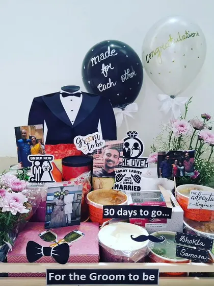 A special hamper for the groom-to-be, counting down to the big day. It includes fresh flowers, a fun tuxedo cutout, and a platter of his favorite foods like Pani Puri, Dhokla, and Pav Bhaji.