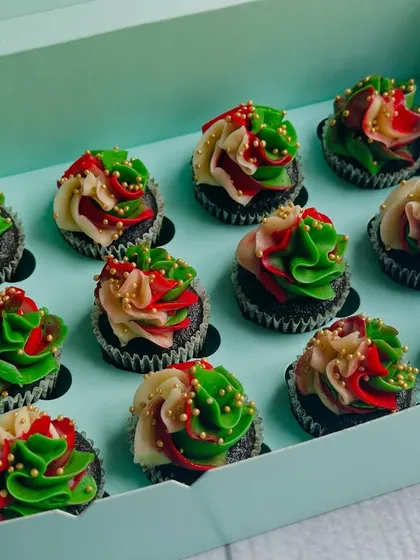 This box features the Christmas cupcakes on a rich chocolate base. The contrast of the dark cake with the bright red and green frosting makes them look extra festive and indulgent.
