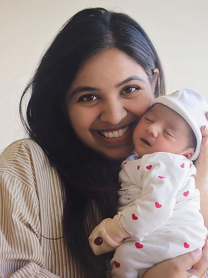 The beautiful, happy smile of a new mom holding her sleeping baby. These lifestyle hospital photos are relaxed and natural, capturing your joy in your own space.