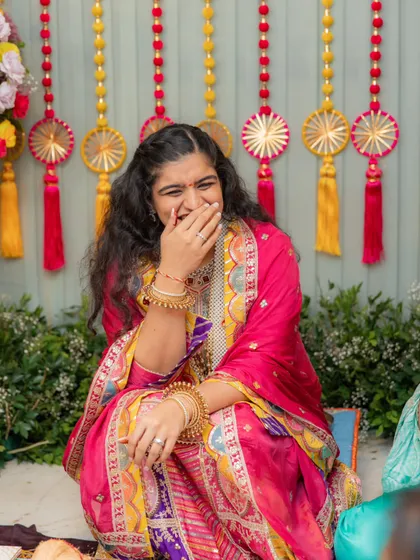 A candid laugh from the bride during her pre-wedding ceremony. This shot captures the joy of the moment and gives a great view of her colorful, traditionally embroidered outfit.