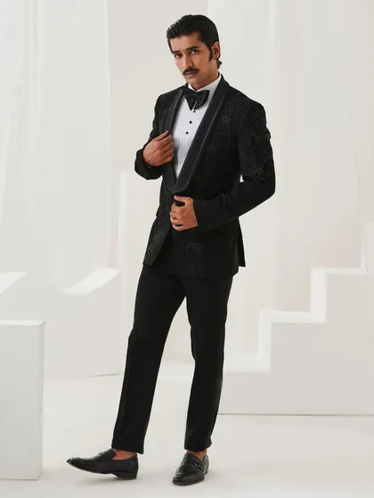 A full-length shot of a black velvet tuxedo from the Nazaakat collection. The subtle tonal embroidery adds a layer of texture and luxury.