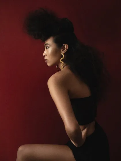 A side profile that emphasizes the sculptural quality of the avant-garde hairstyle. This shot is all about form, silhouette, and the elegant line of the model's pose.