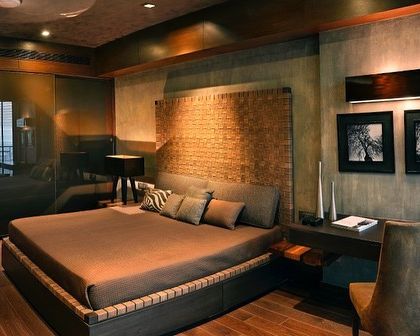 A bedroom in the Magnolias apartment, designed as a moody and masculine retreat. A woven leather headboard, dark wood tones, and textured walls create a rich and enveloping atmosphere.