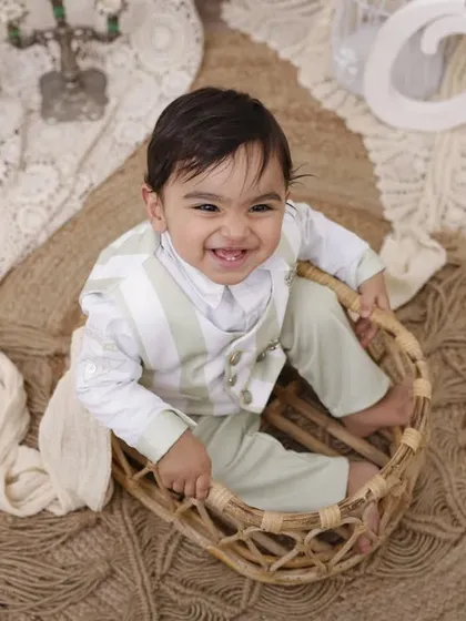 That big, beautiful smile says it all. We captured this moment of pure happiness during his first birthday session, using a bright, bohemian-inspired setup with natural textures.