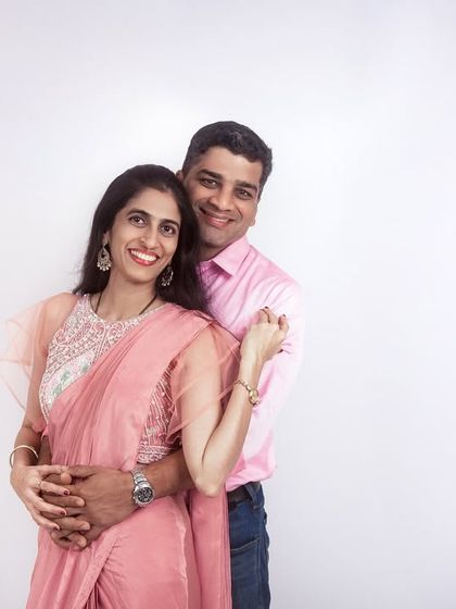 A loving couple's portrait in the studio. The simple white background and coordinated pink outfits create a soft and romantic image.