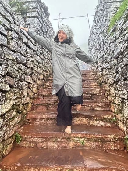 A happy trekker on the stone steps of a fort in Chikmagalur, enjoying the rainy weather.