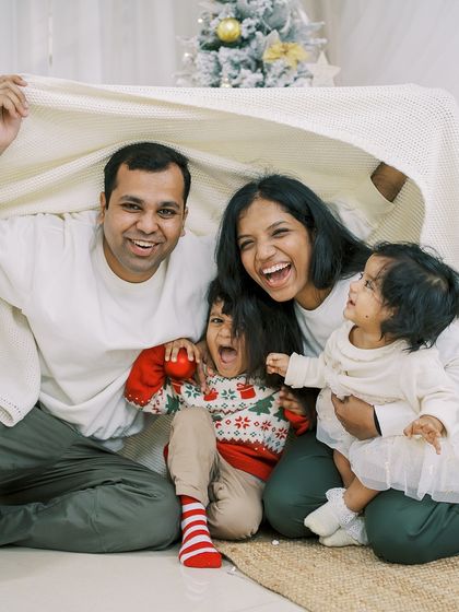 A family playing together under a blanket, full of laughter. A perfect candid moment from a Christmas session.