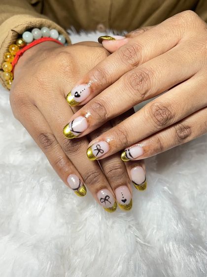 A closer look at the gold chrome French tips with the delicate bow art. The combination of the metallic finish and the cute design is very unique.