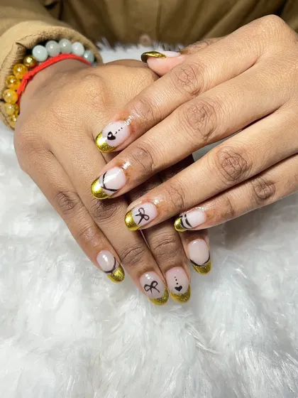 A closer look at the gold chrome French tips with the delicate bow art. The combination of the metallic finish and the cute design is very unique.