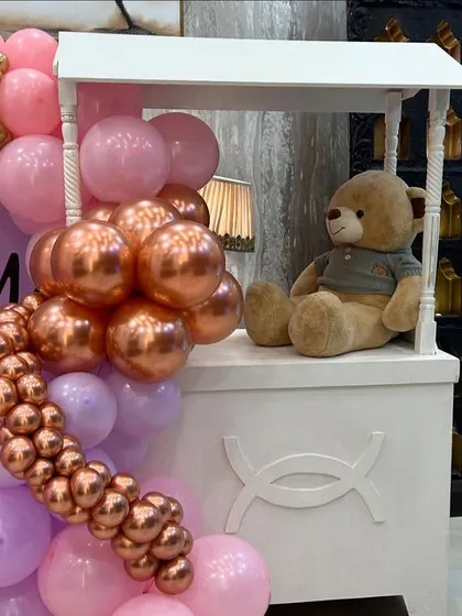 A sweet teddy bear sits on a white cart, perfectly integrated into the balloon decor. These little details bring our themes to life.