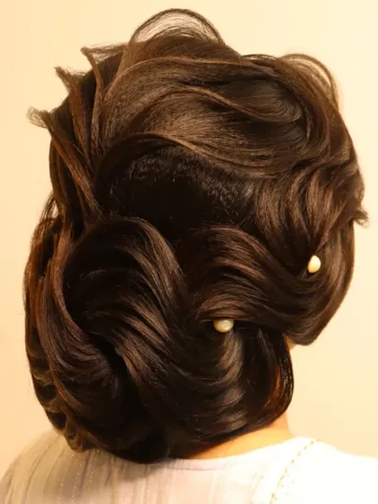 An elegant wedding day hairstyle featuring sweeping S-waves pinned into a low bun. This is a chic and sophisticated look, perfect for a modern bride.