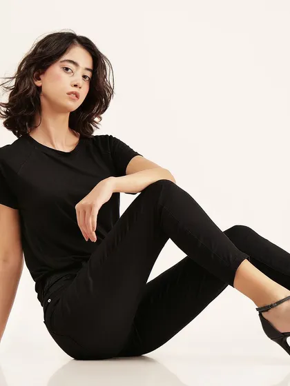 A relaxed, floor-seated pose that showcases the comfortable fit of the black t-shirt and pants.