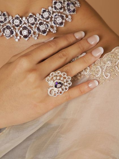 A close-up of the ring from our new Polki diamond collection. The deep purple stone is surrounded by an intricate floral design of sparkling stones, making it a true statement piece.