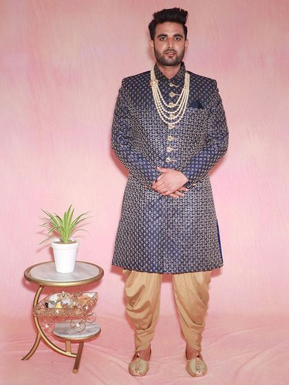 This navy blue printed Indo-western jacket paired with dhoti pants is a perfect blend of traditional and modern. The pearl mala adds a touch of regal elegance.