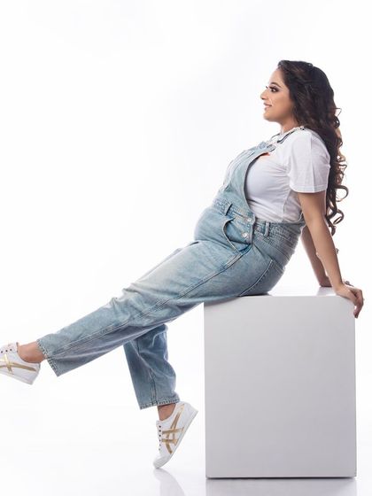 A relaxed and happy portrait of a mom-to-be in denim dungarees. This casual outfit choice is perfect for a comfortable and playful maternity session.