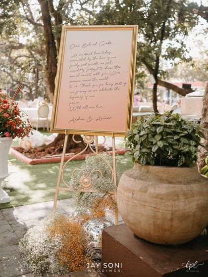 A simple yet heartfelt welcome. This elegant sign with a personal message from the couple, set on a golden easel and adorned with baby's breath, adds a warm and intimate touch to the wedding entrance.