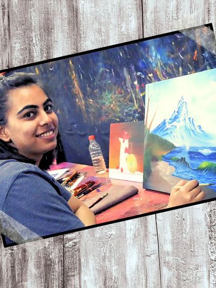 A student smiling while working on her landscape painting in the studio. Our classes are not just about learning; they are about finding joy in art.