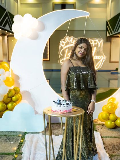 The birthday girl standing by the cake, with the glowing moon backdrop creating a beautiful, ethereal ambiance.