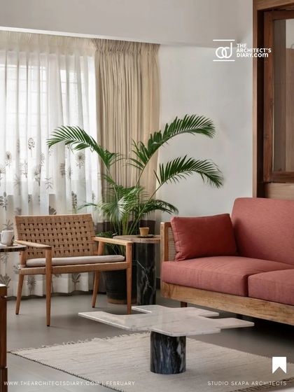 A magazine photo of the family lounge, showcasing the mix of textures with a woven armchair, a plush sofa, and marble coffee tables, all contributing to the warm, layered Japandi feel.