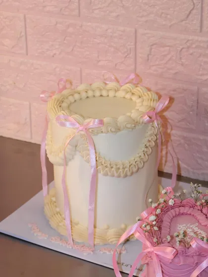 Another angle of our princess-inspired vintage cake, showing how the delicate pink ribbons and piped swirls come together for a truly elegant design.