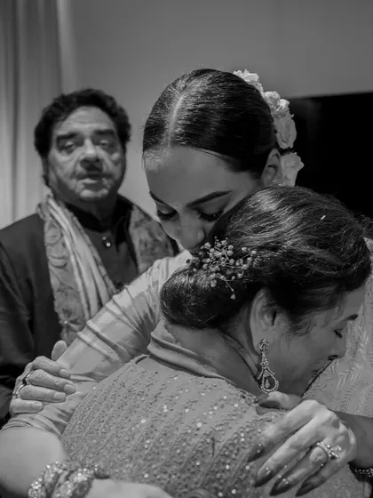 A bride shares a three-way hug with her parents just before walking to her groom. This black and white image beautifully captures the emotion and unity of the family in this significant moment.
