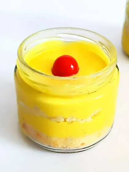 This is our Mango Charlotte cake jar. It features layers of light sponge and creamy mango mousse, topped with a cherry. These jars are a convenient and elegant dessert option for events.