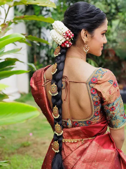 A traditional South Indian hairstyle is a work of art. This classic braid, adorned with fresh jasmine and intricate gold accessories (jadai), is the perfect complement to a silk saree for a wedding or half saree ceremony.