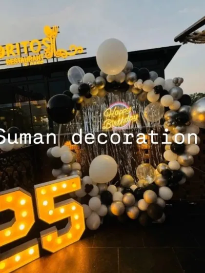 A 25th birthday setup at a restaurant terrace, with a black, white, and silver balloon ring and large marquee numbers.