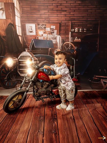A joyful moment in the garage. This little mechanic is all smiles as he stands by his motorcycle, ready for his next ride.
