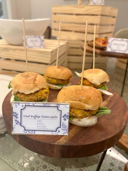 A close-up of our fried truffled chicken sliders. These bite-sized burgers are served on a wooden platter, each held together with a skewer, showcasing our attention to detail and gourmet flavor combinations.