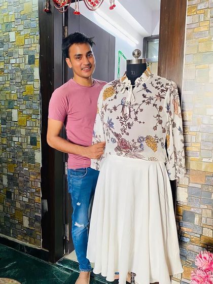 A happy client with his custom-designed two-piece outfit, featuring a printed top with bell sleeves and a simple white skirt.