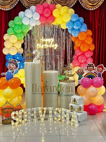 A vibrant Cocomelon stage decoration with a rainbow balloon arch and a shiny fringe backdrop. I use multiple character cutouts and custom light-up letters to create a fun and personalized party scene.