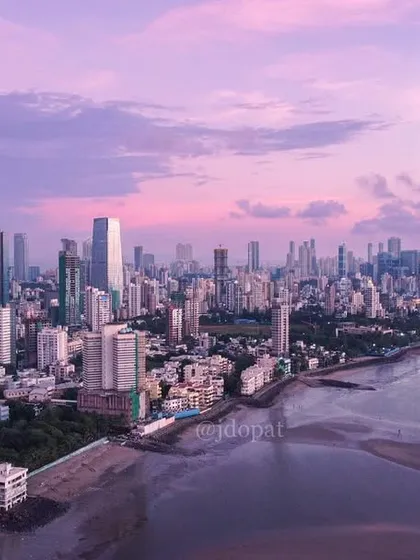 A beautiful aerial view of Mahim Bay in Mumbai, with the water and sky bathed in a soft purple light at dusk.