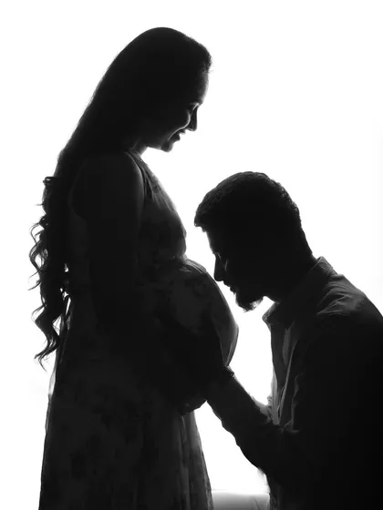 A dreamy maternity silhouette. The way he kneels to kiss her belly is a classic and beautiful gesture, made even more artistic in this high-contrast style.
