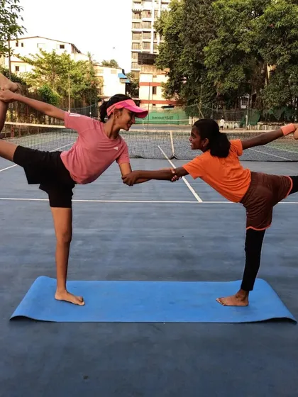 Partner yoga helps build trust and communication between players. This standing bow pose requires balance and coordination, reflecting the synergy needed in doubles play.