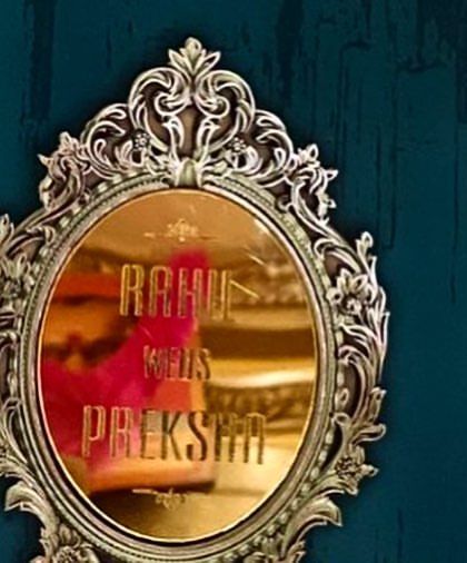 A design that is pure modern luxury. This invitation features a custom nameplate designed to look like an ornate, golden mirror, set against a deep teal background with floral accents.