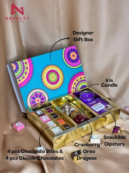 This hamper is a festive feeling in a box. The vibrant designer box with a golden base contains an assortment of classic and flavored chocolate bites, cranberry and oreo dragees, and an Iris candle for a complete sensory experience.