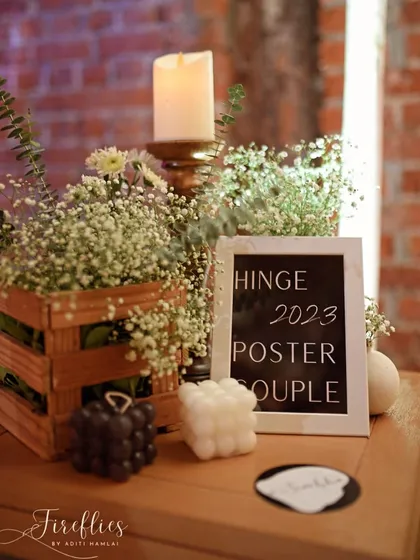 Personal details on a side table, including a sign that reads "Hinge 2023 Poster Couple," telling a small part of the couple's love story.