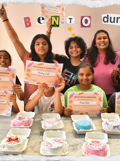 The proud graduates of our Bento Cake Kids Workshop! Each little chef is holding their certificate of completion and showing off the mini cake they baked and decorated all by themselves.