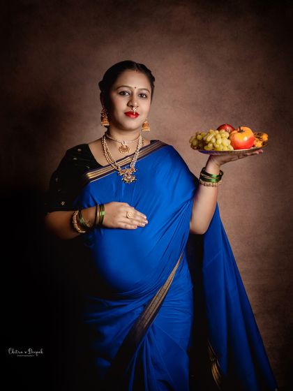A beautiful portrait of a mom-to-be in a vibrant blue saree, holding a platter of fruit, reminiscent of traditional ceremonies.