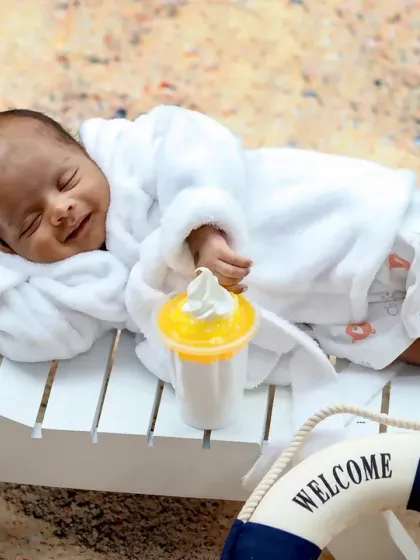A newborn enjoys a relaxing nap on a miniature beach lounge chair, dreaming of the ocean.