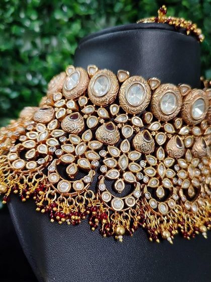 A close-up angle of this heavy kundan choker, showing the incredible density of the stonework and the delicate red bead accents.