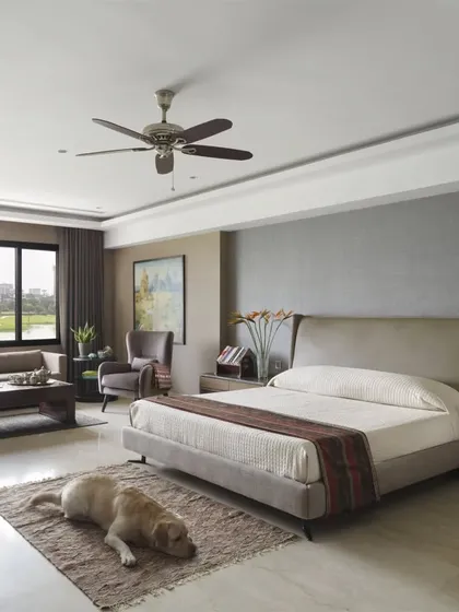 The spacious master bedroom in the Caitriona apartment, offering serene views of the golf course. The design creates a restful atmosphere with a calm color palette and a comfortable seating area.