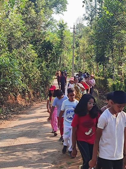 A line of young campers walks along a path during a guided nature trek at our Barapole summer camp.