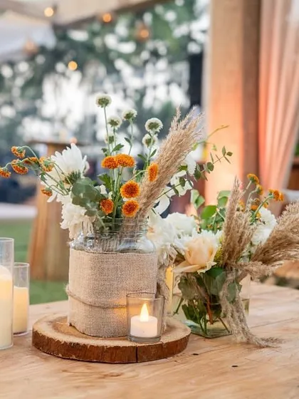 A rustic centerpiece on a wooden table, combining burlap, candles, and wildflowers for an earthy, natural feel.