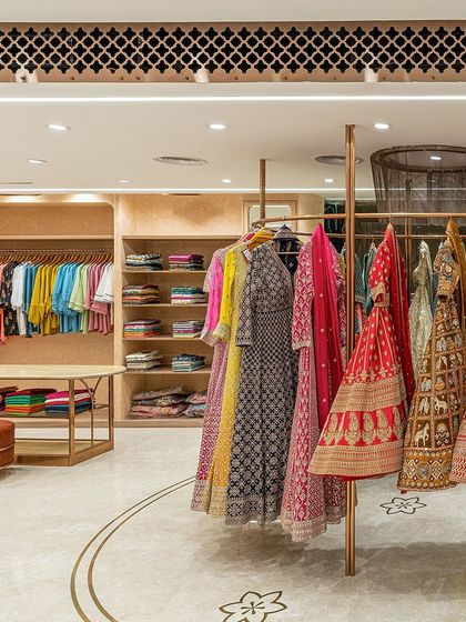 A detail of the ready-to-wear section, where colorful garments are displayed against a backdrop of light wood shelving. The design is clean and organized, making it easy for customers to browse.