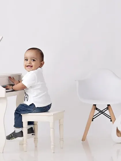 The mini-maestro seated at his piano, flashing an adorable smile for the camera.