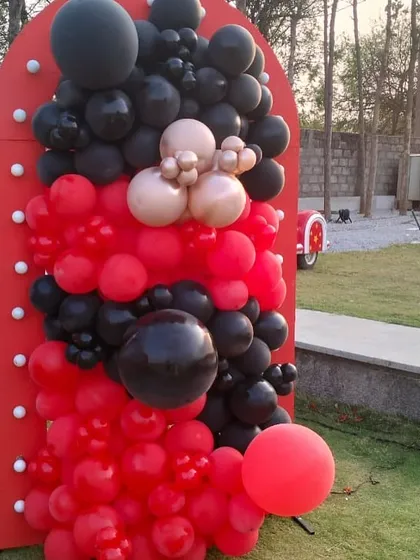 A bold red and black balloon arrangement against a custom prop for the Vedsvillie Station theme. This close-up shows the detail and striking color combination used to create the vintage railway atmosphere.