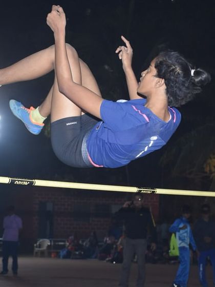 A high jumper soars over the bar under the lights at TrackNights. Registrations are open for our next event.