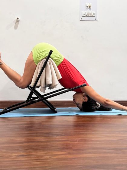Here, a chair is used to modify Adho Mukha Svanasana (Downward-Facing Dog) for a deeper stretch in the shoulders and upper back. This variation is particularly useful for releasing tension and creating space in the thoracic spine.